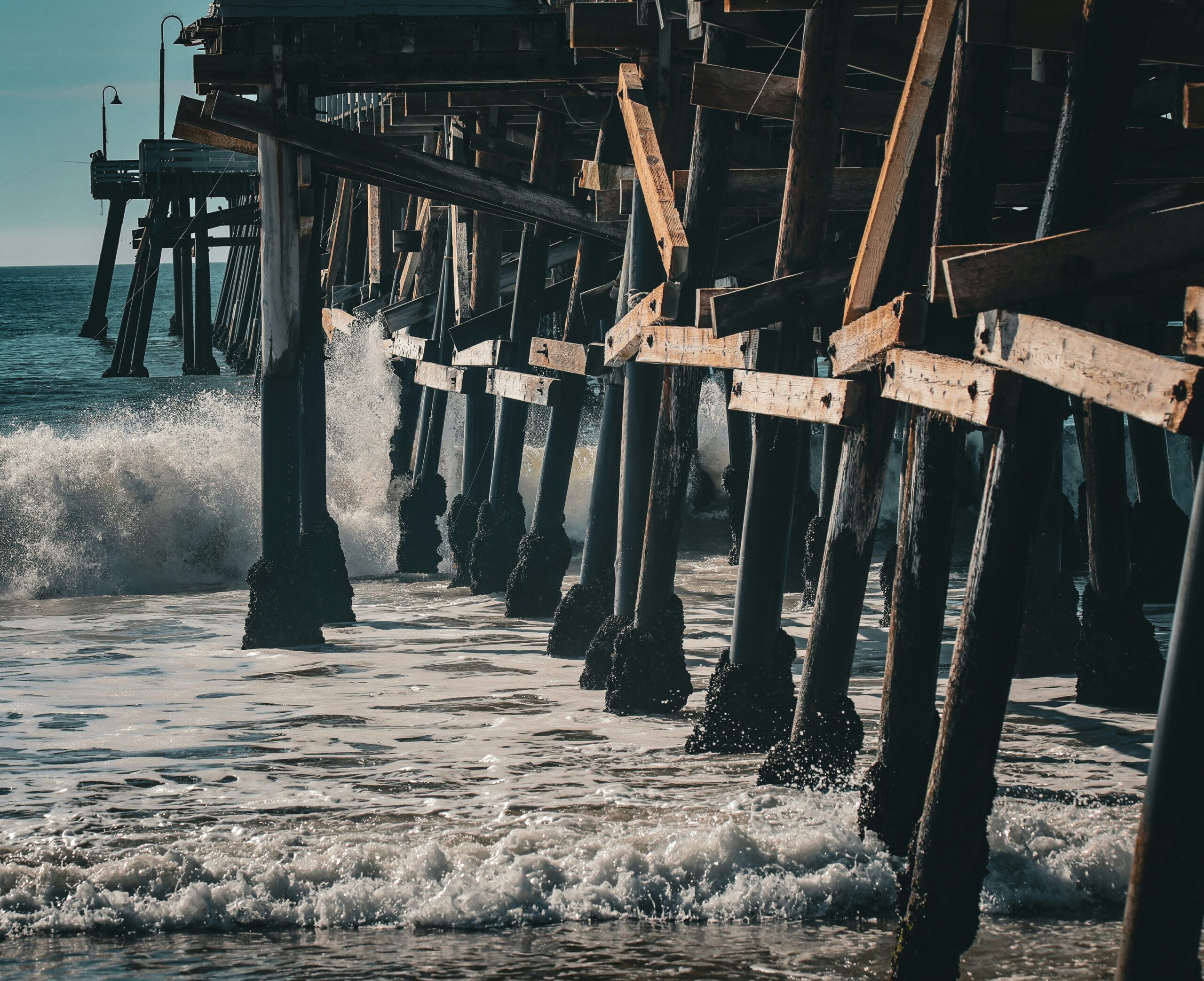 Waves crashing under the wooden pilings of the San Clemente pier