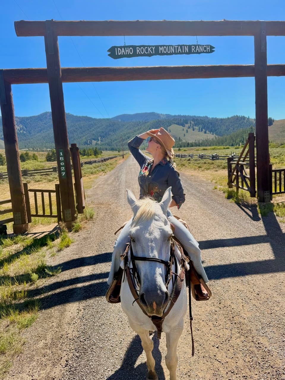 Kami on horseback beneath the Idaho Rocky Mountain Ranch entrance sign in the Sawtooth Valley